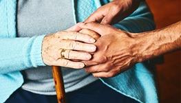 Person providing help and elder care to woman with a cane