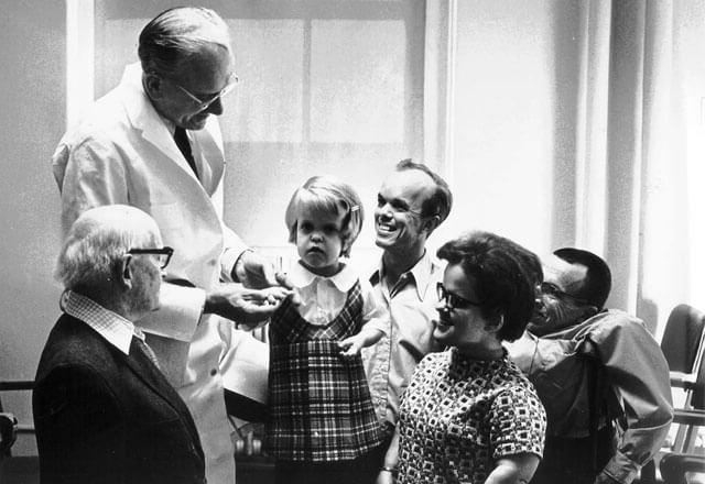 Doctor standing and talking with early genetics research participants