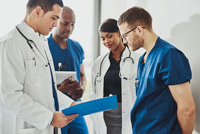 Four doctors in lab coats looking at an open folder